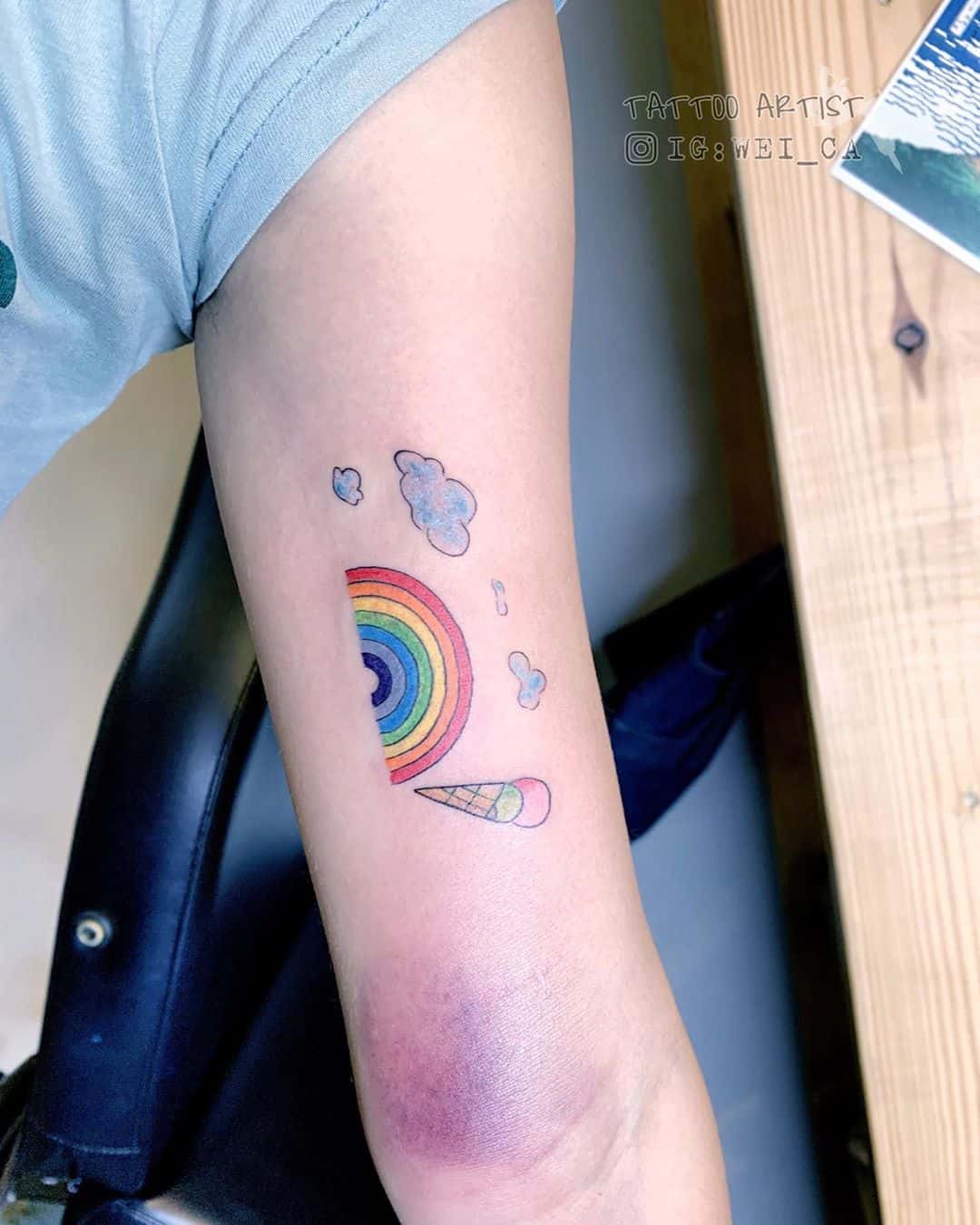 Tiny rainbow tattoo located on the lower back