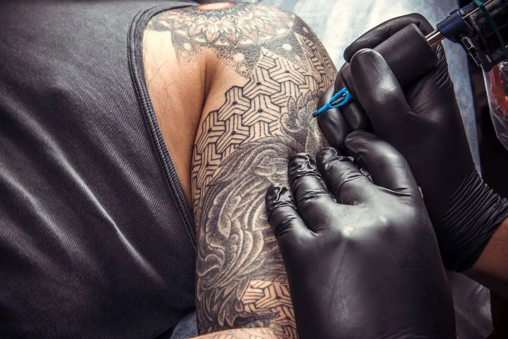 tattoo artist give a black sleeve to a man