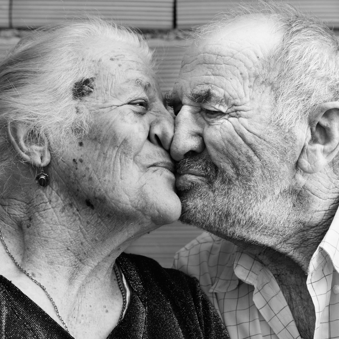 portraits of two elderly kissing in black and white photo
