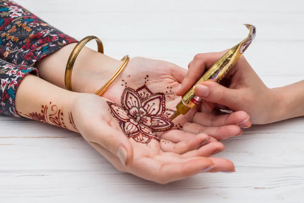 professional henna tattoo being applied to the palms of a women
