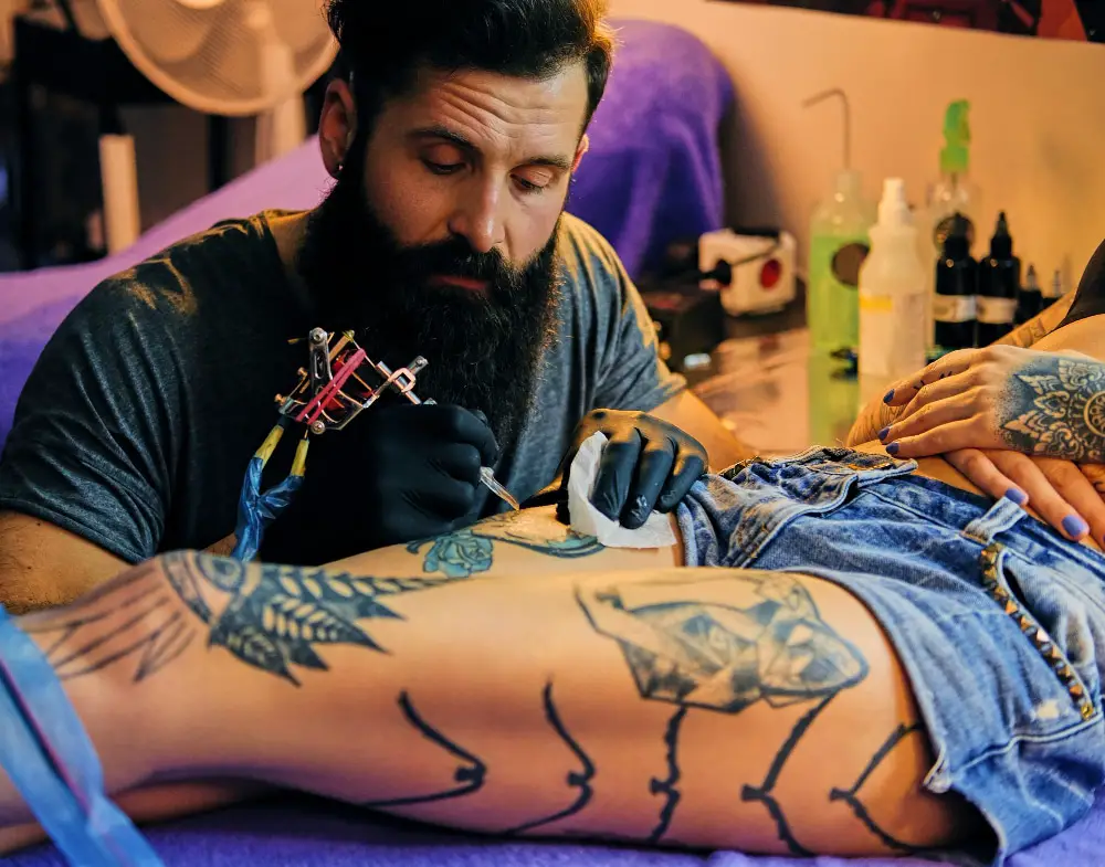 tattoo artist giving large colourful tattoo to women
