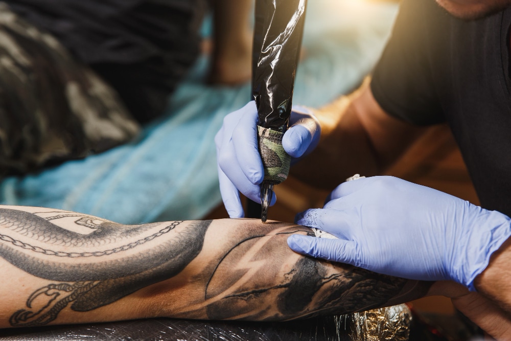 tattoo artist creating a black tattoo sleeve on a many