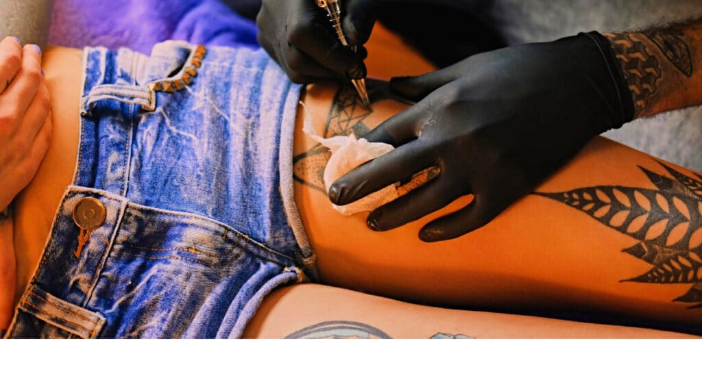 tattoo artist giving a women a leg tattoo