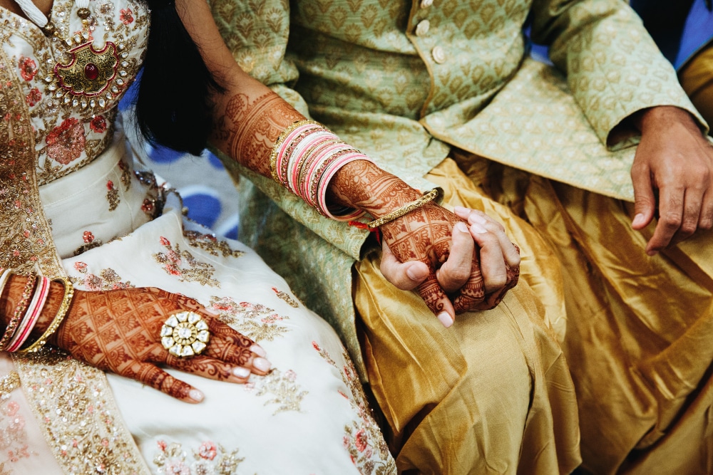 indian couple holing hands with dark henna too up arm
