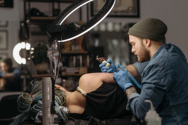 male tattoo artist doing arm tattoo