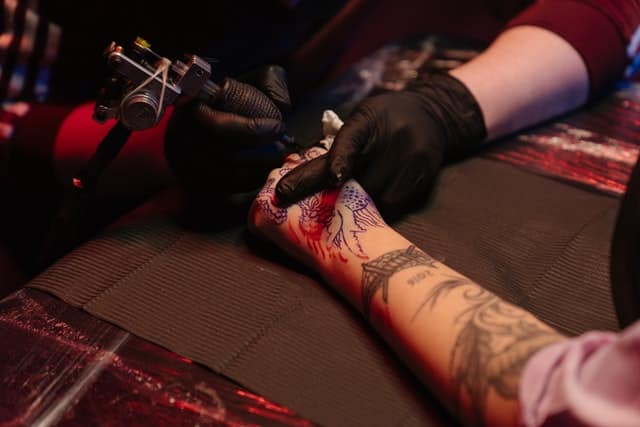 male tattoo artist giving arm tattoo
