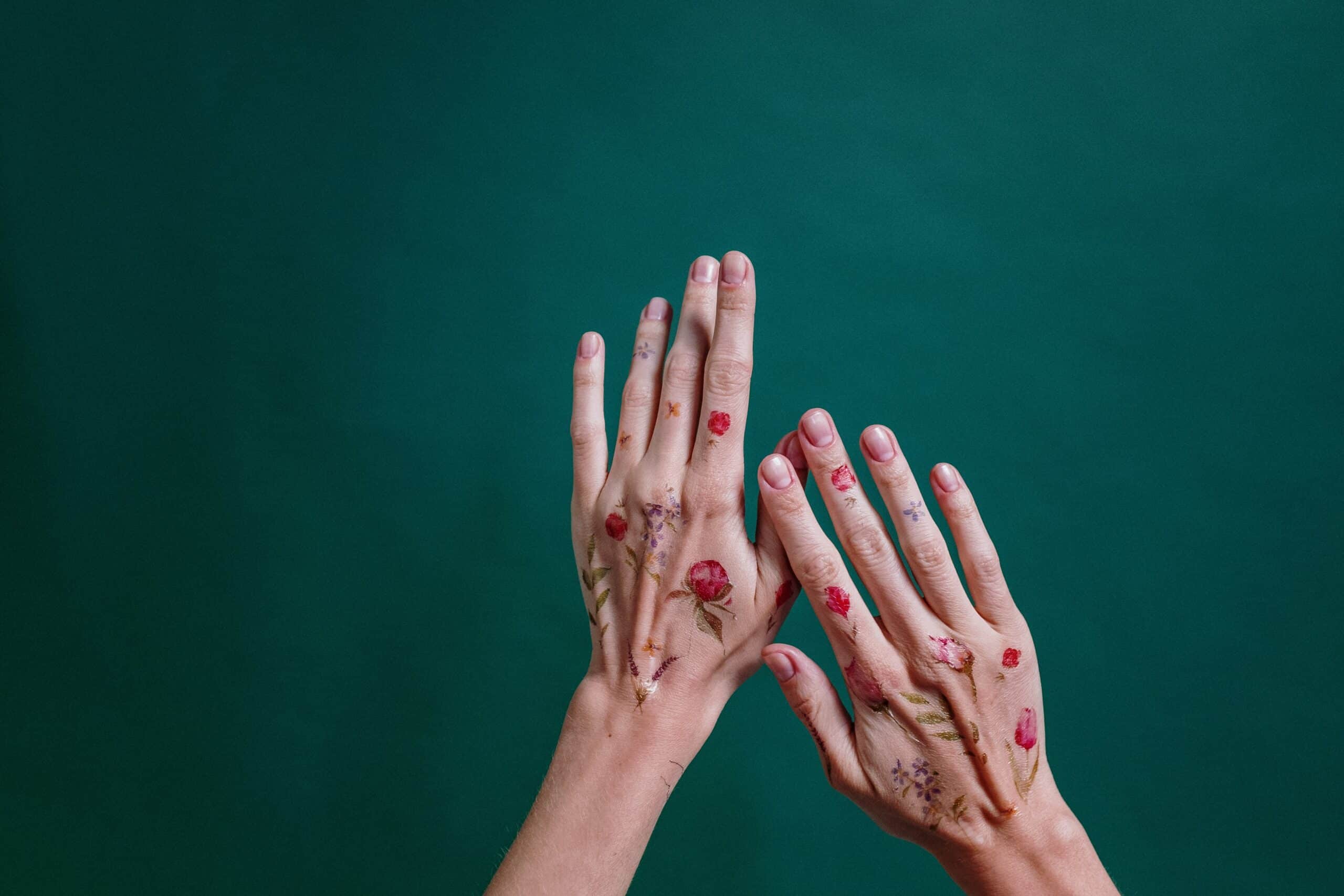 hands covered in colorful floral temporary tattoos