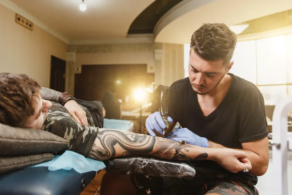 arm sleeve tattoo being put on  by tattoo artist in shop