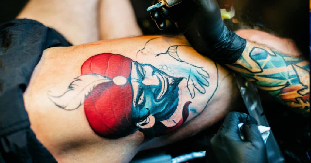 tattoo artist give a man a leg tattoo