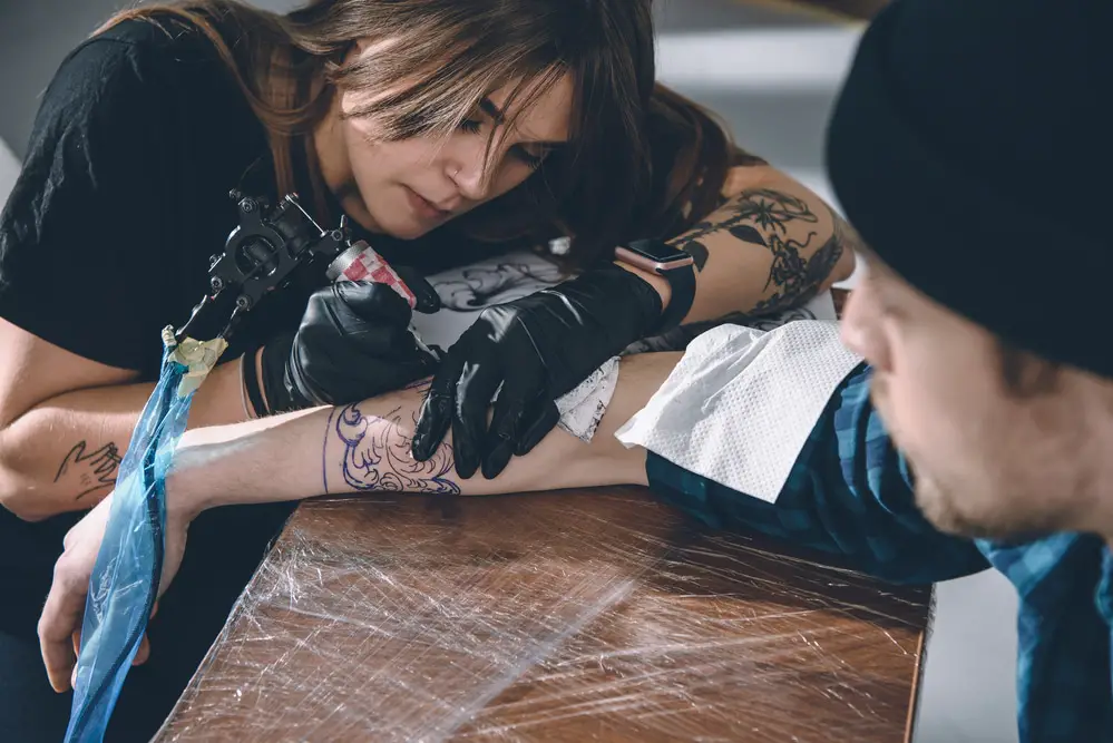 female tattoo artist giving a tattoo over stretch marks