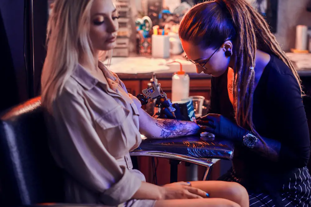 beautiful blonde women getting a colorful tattoo on her arm