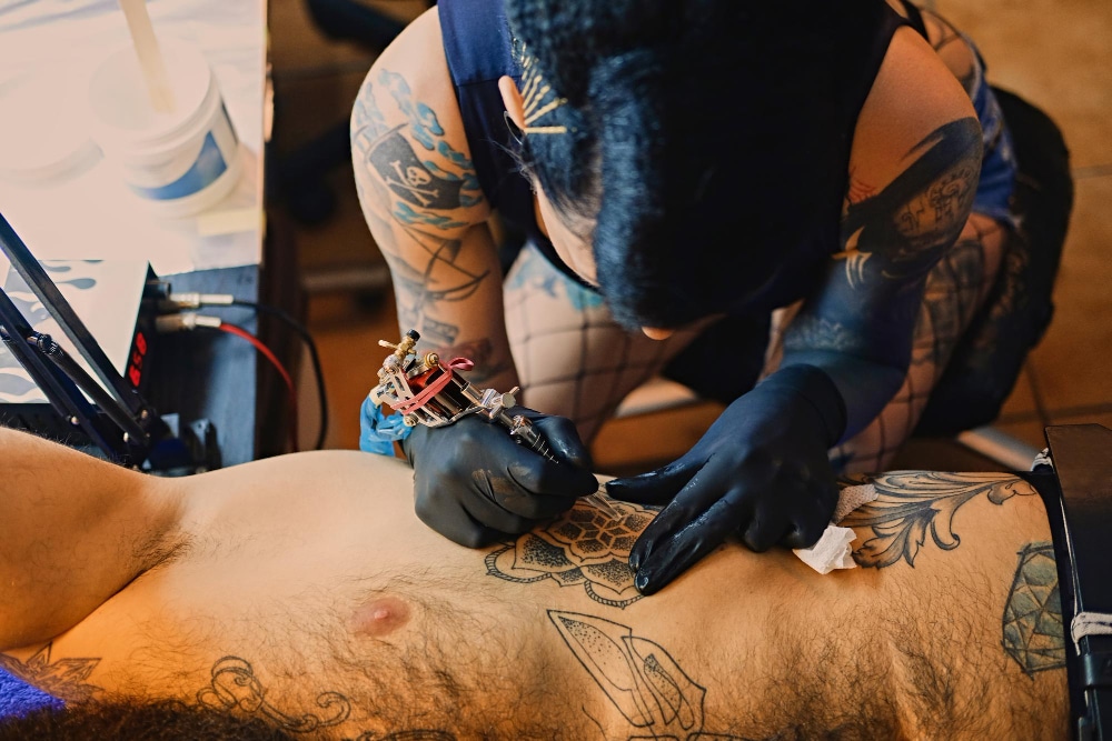tattoo artist giving a strong man a tattoo on his stomach