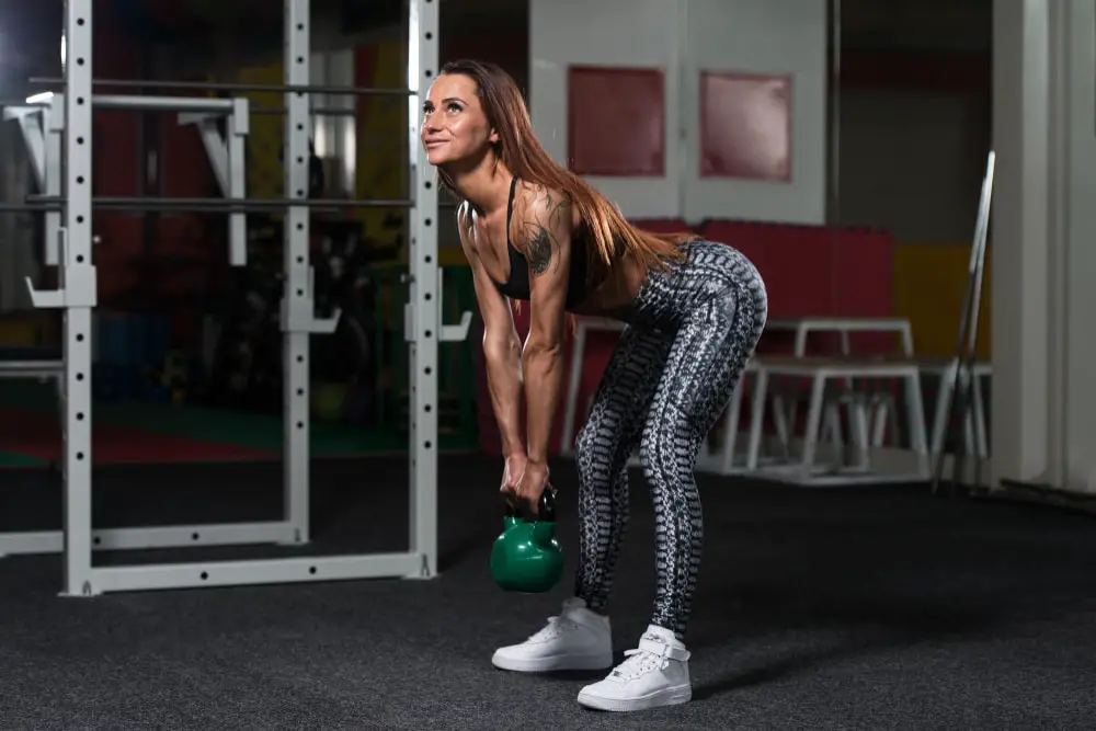 pretty women training with tattoos training with kettlebells in the gym
