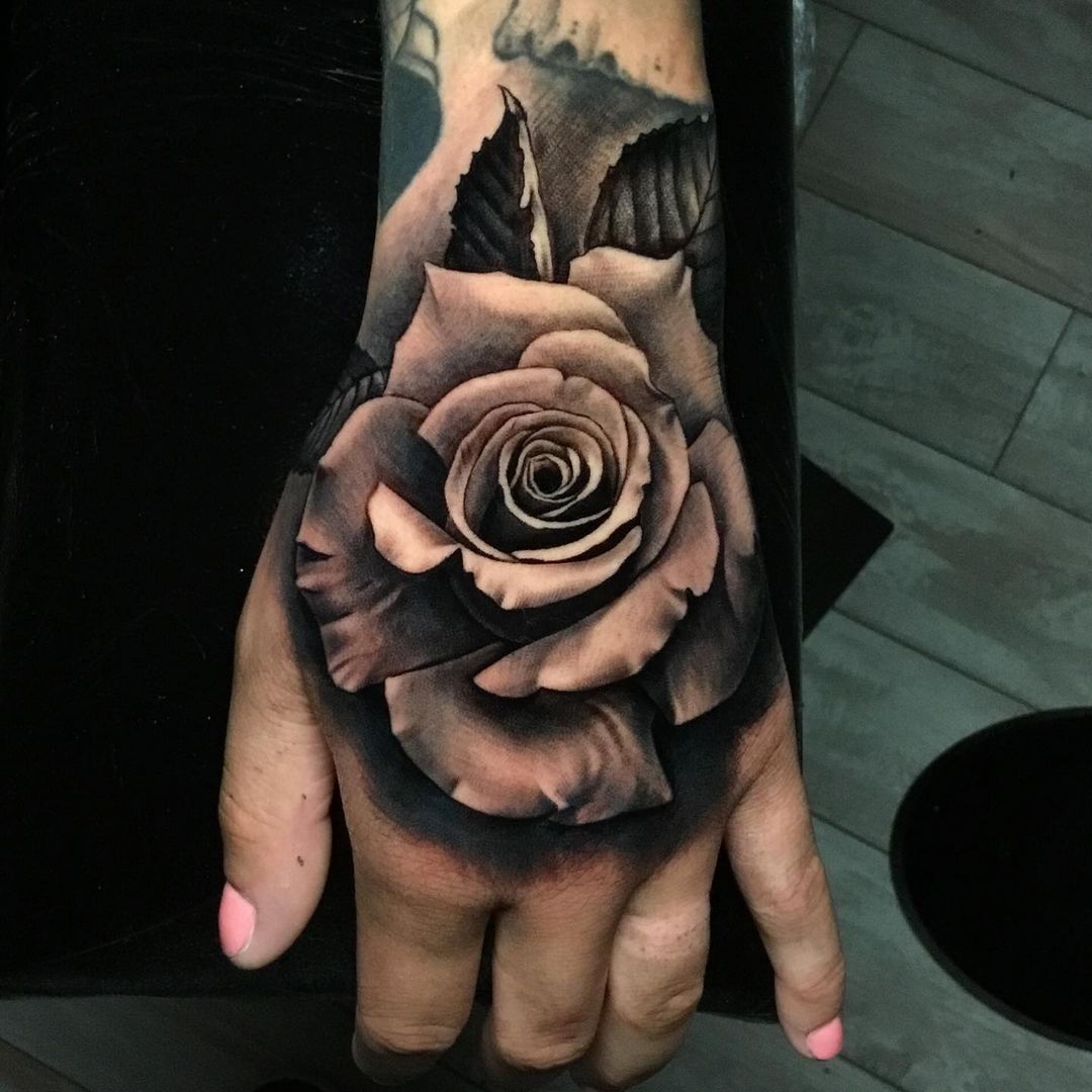 black and gray rose tattoo on mans hand