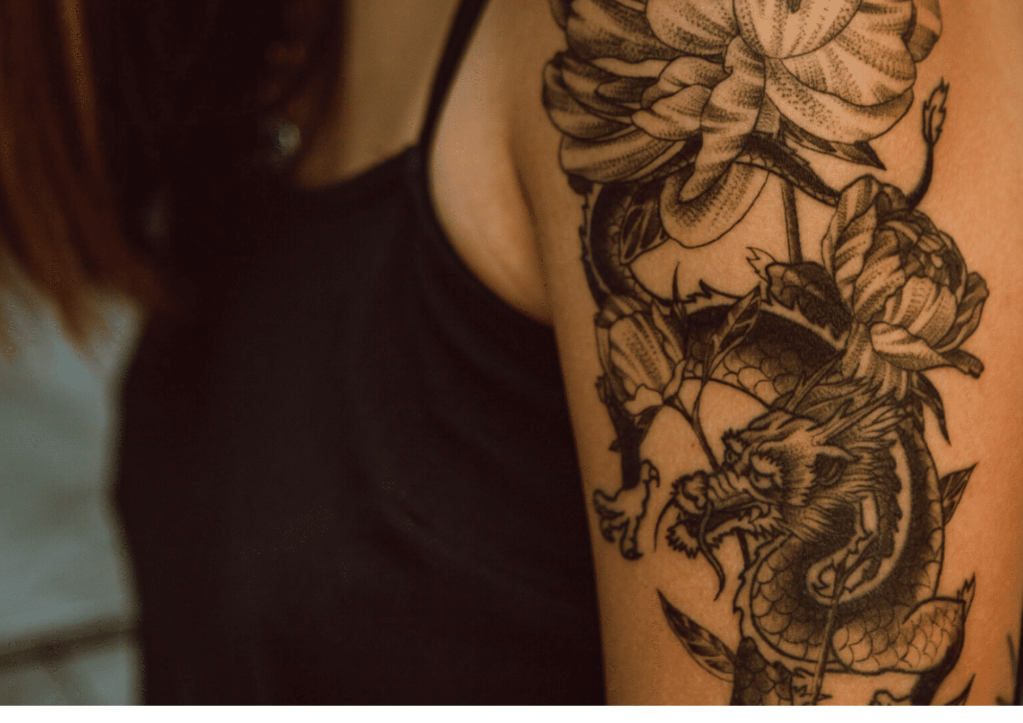 a woman with dragon and flower tattoos on her arm