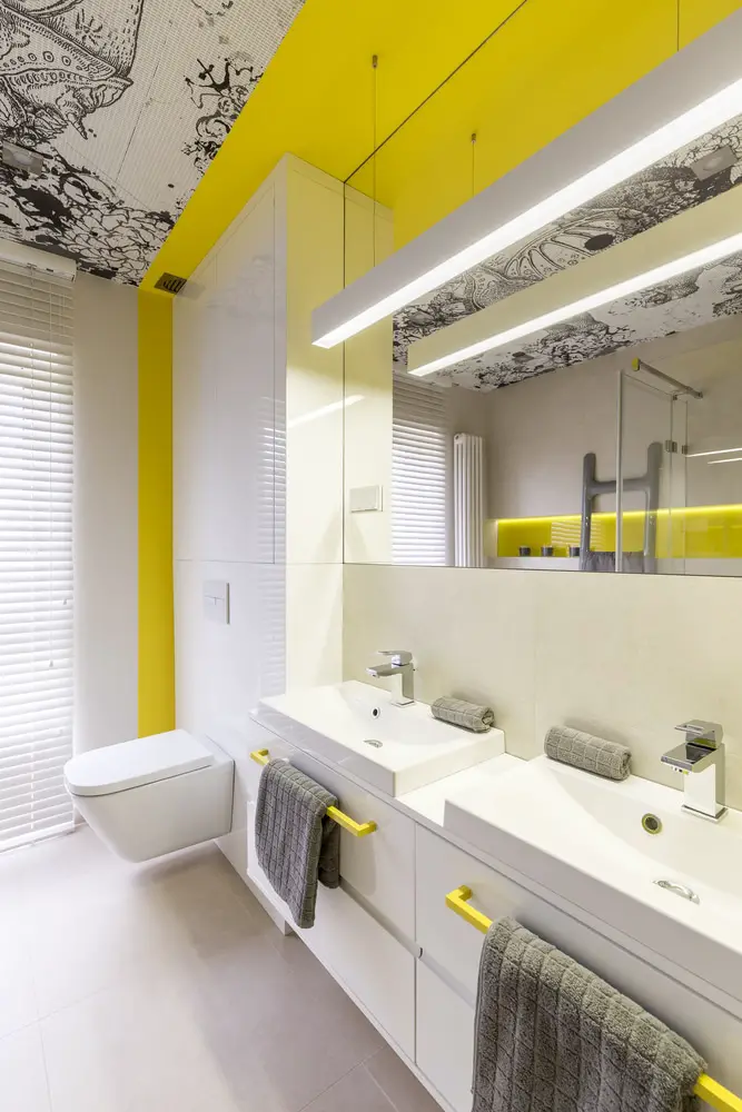 a trendy bathroom with black doodled artwork and accents of neon yellow palettes