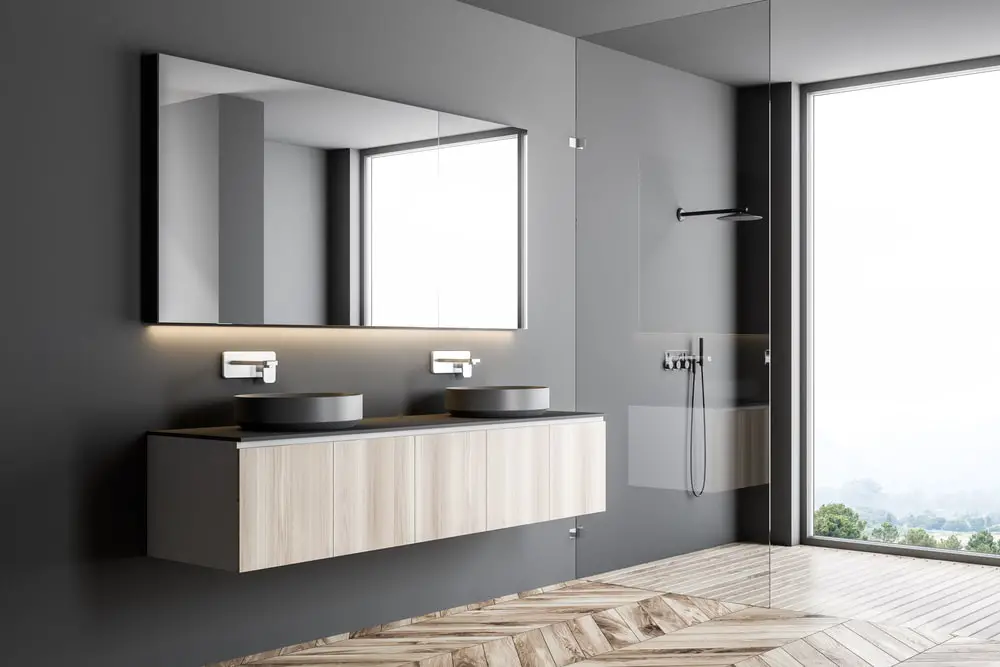 silky dark gray walls with panoramic mirror, twin chrome lavatory on wall-mounted storage cabinet 