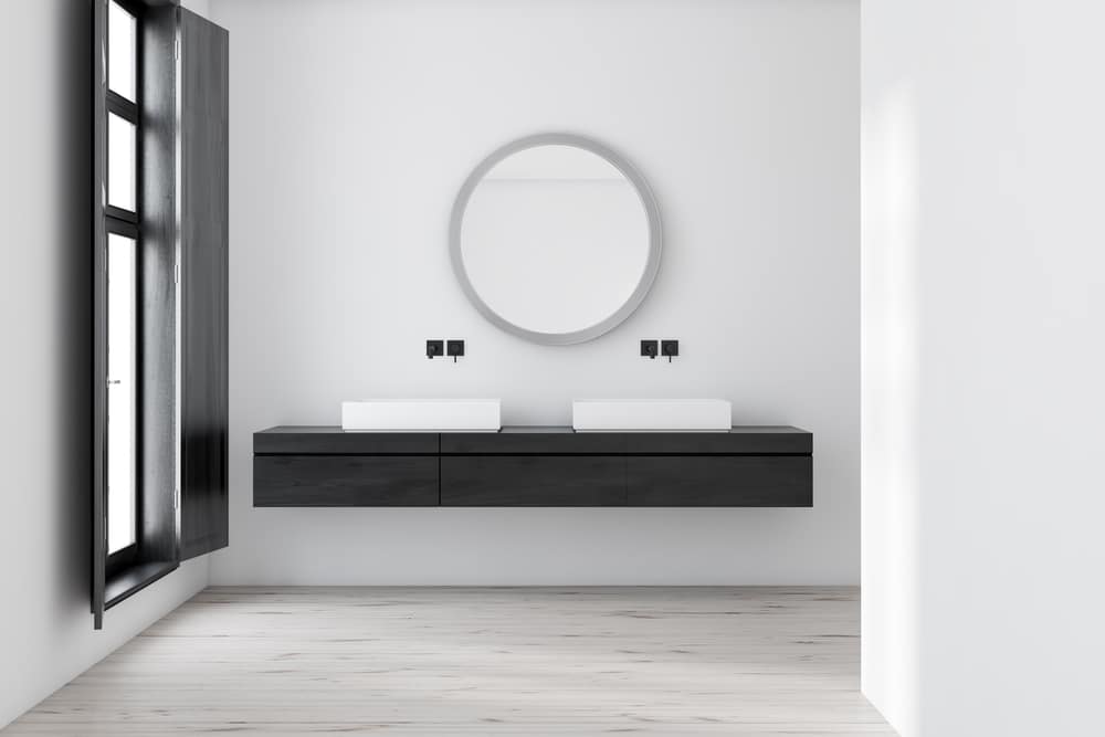 sleek white walls with round mirror and twin lavatory