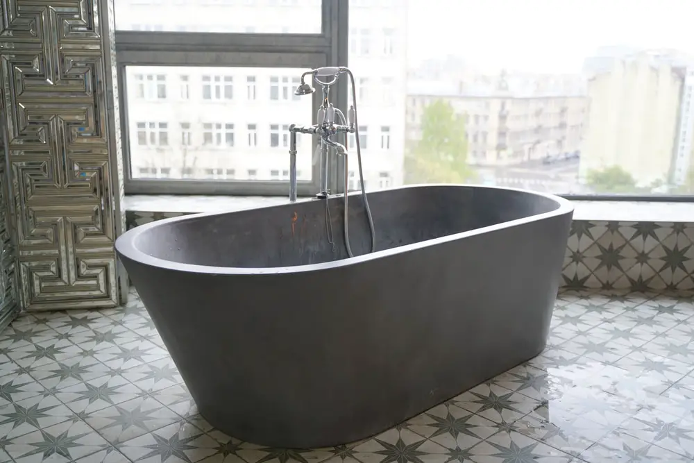freestanding bath tub with grecian patterned mirrored divider