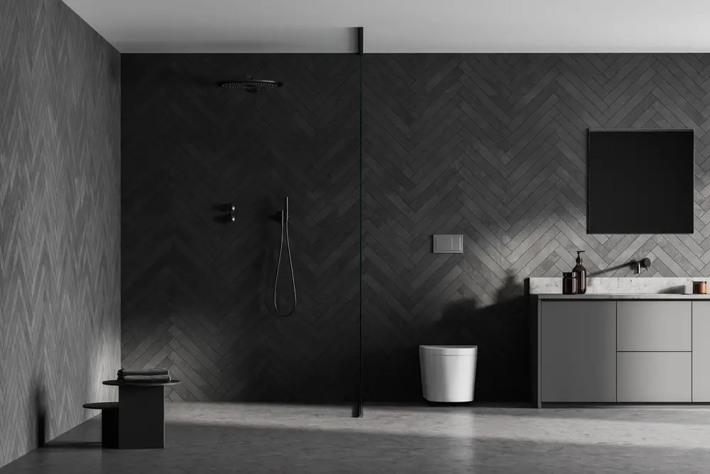 a dark gray bathroom design with parquet wall tiles. freestanding tub. and minimalist bathroom fixtures
