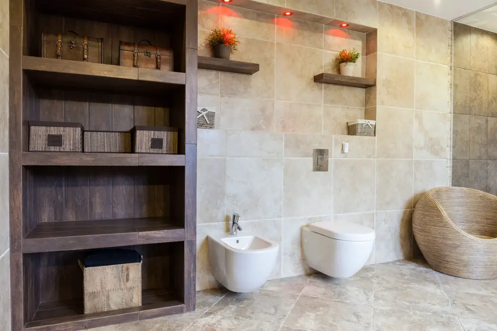 a luxurious oriental bathroom design with wooden solid dark wood storage, wall mounted toilet and woven accent chair