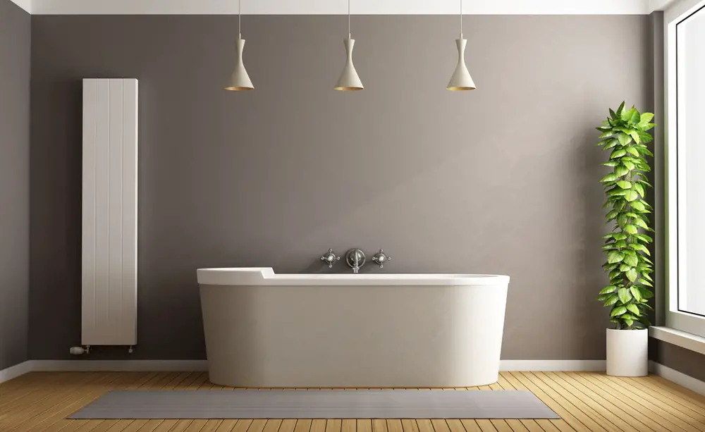 minimalist oriental bathroom with stand alone matte finish creamy white tub, potted upright tub gray walls, wood palette flooring and three cone pendant light