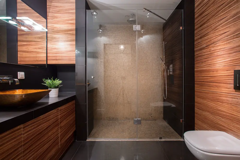 a modern oriental bathroom design with mosaic wall tiles and reddish brown wood veneer and acrylic tabletop lavatory