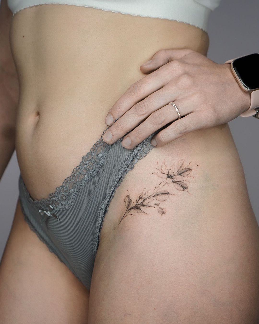 tiny flower tattoo on the pelvic of a woman