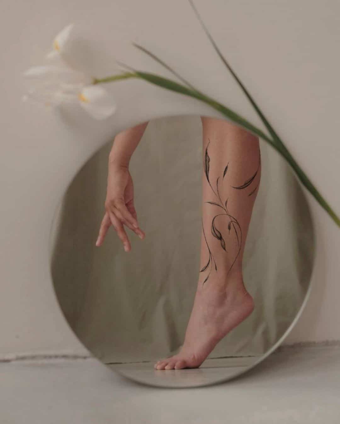 flowing flower tattoo on the legs of a woman