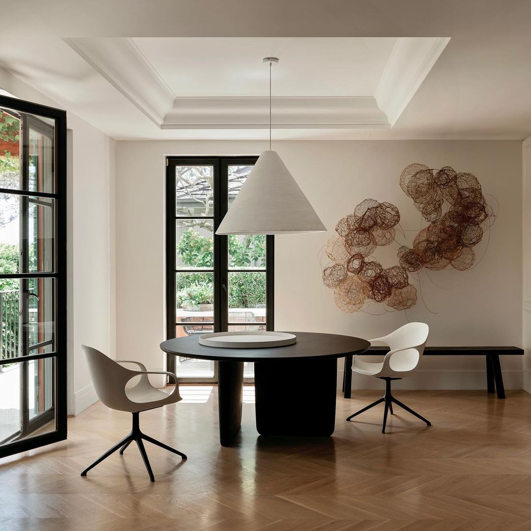 a dining room with inverted cone chandelier and an abstract wall piece