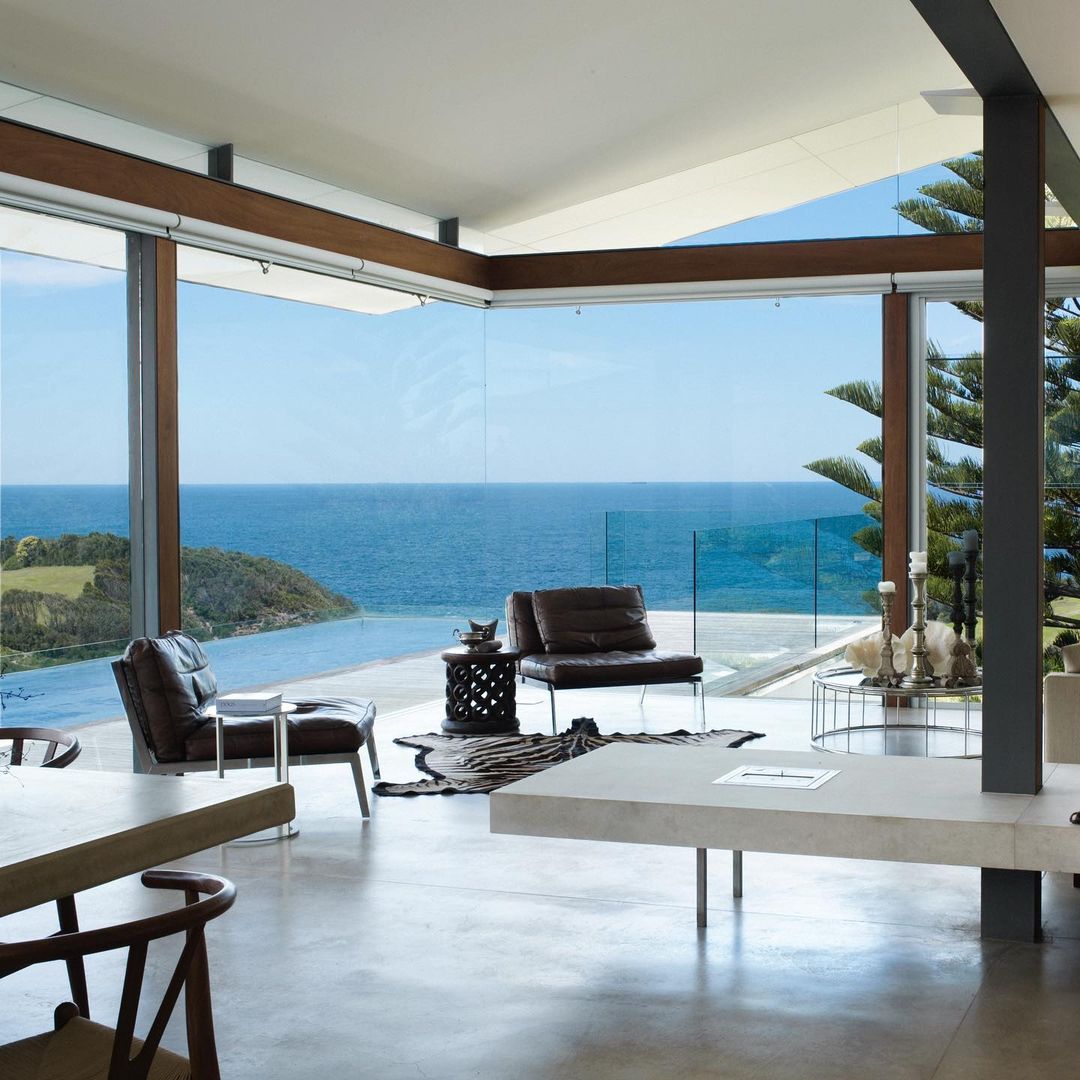 a living room with glass walls overlooking an ocean