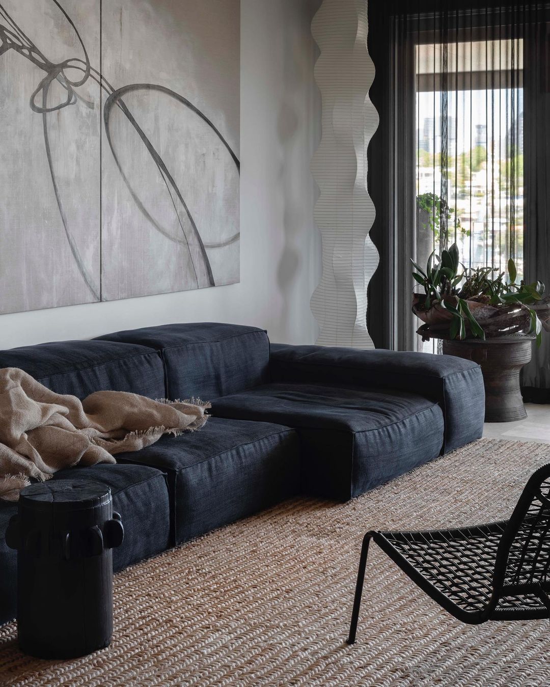 a living room with black sofa and japanese inspired floor lamp