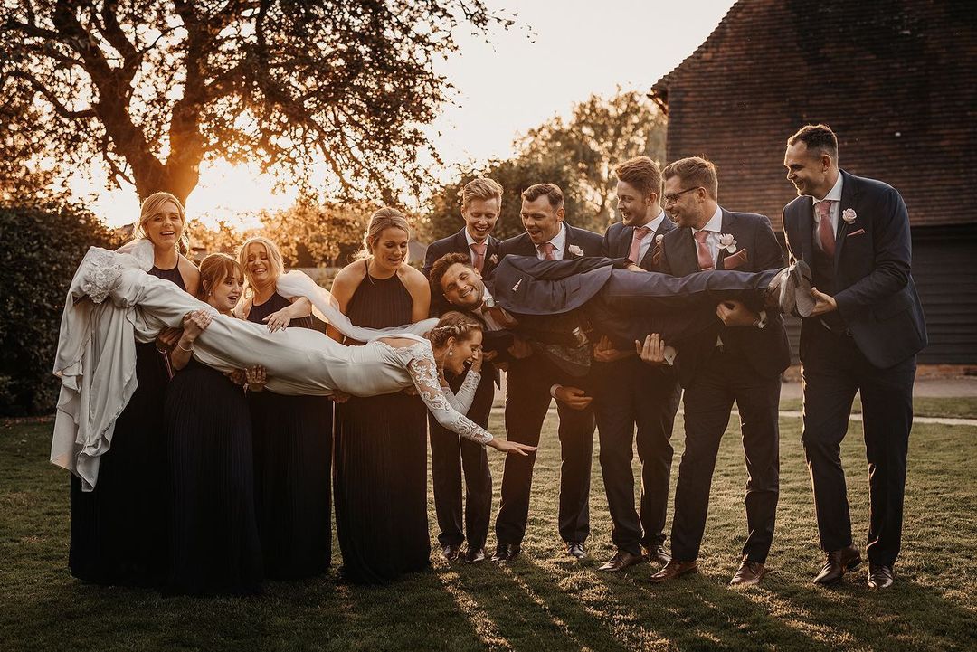 a fun wedding picture of the bride and groom being carried by bridesmaids and best men
