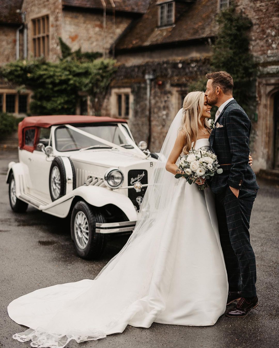 a romantic picture of a newly wed couple with their classic wedding car