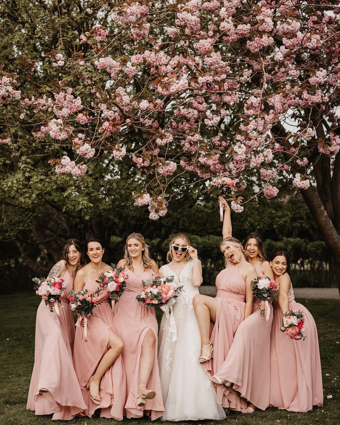 a picture of the bride and her bridesmaid wearing soft pink dress under a flowering tree