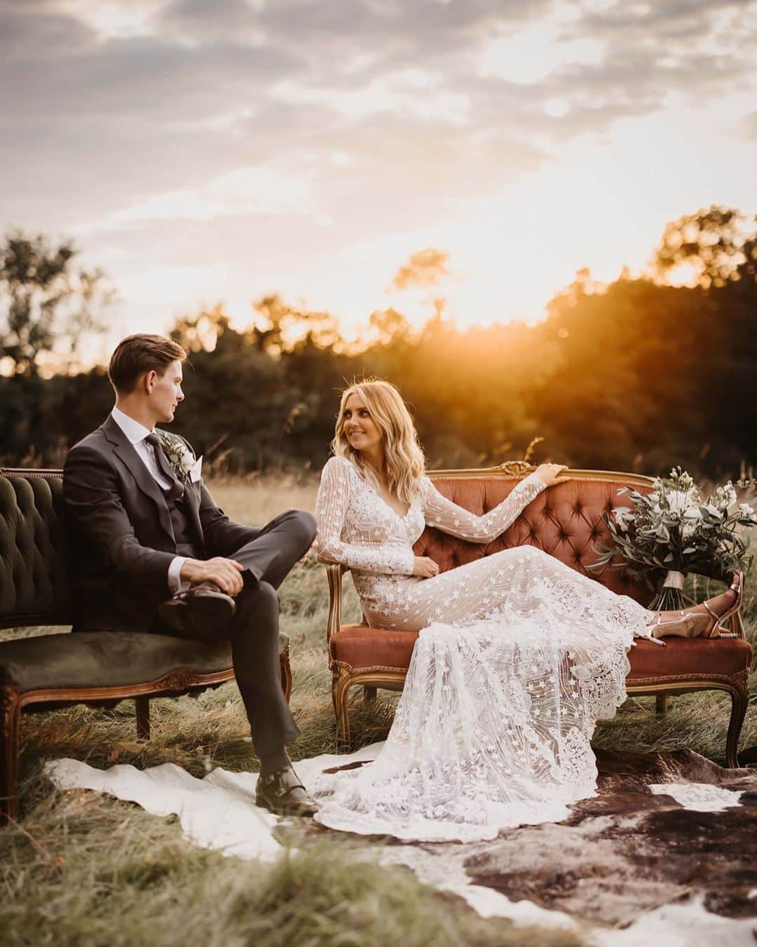 a picture of a newlywed couple sitting on a tufted sofa outdoors