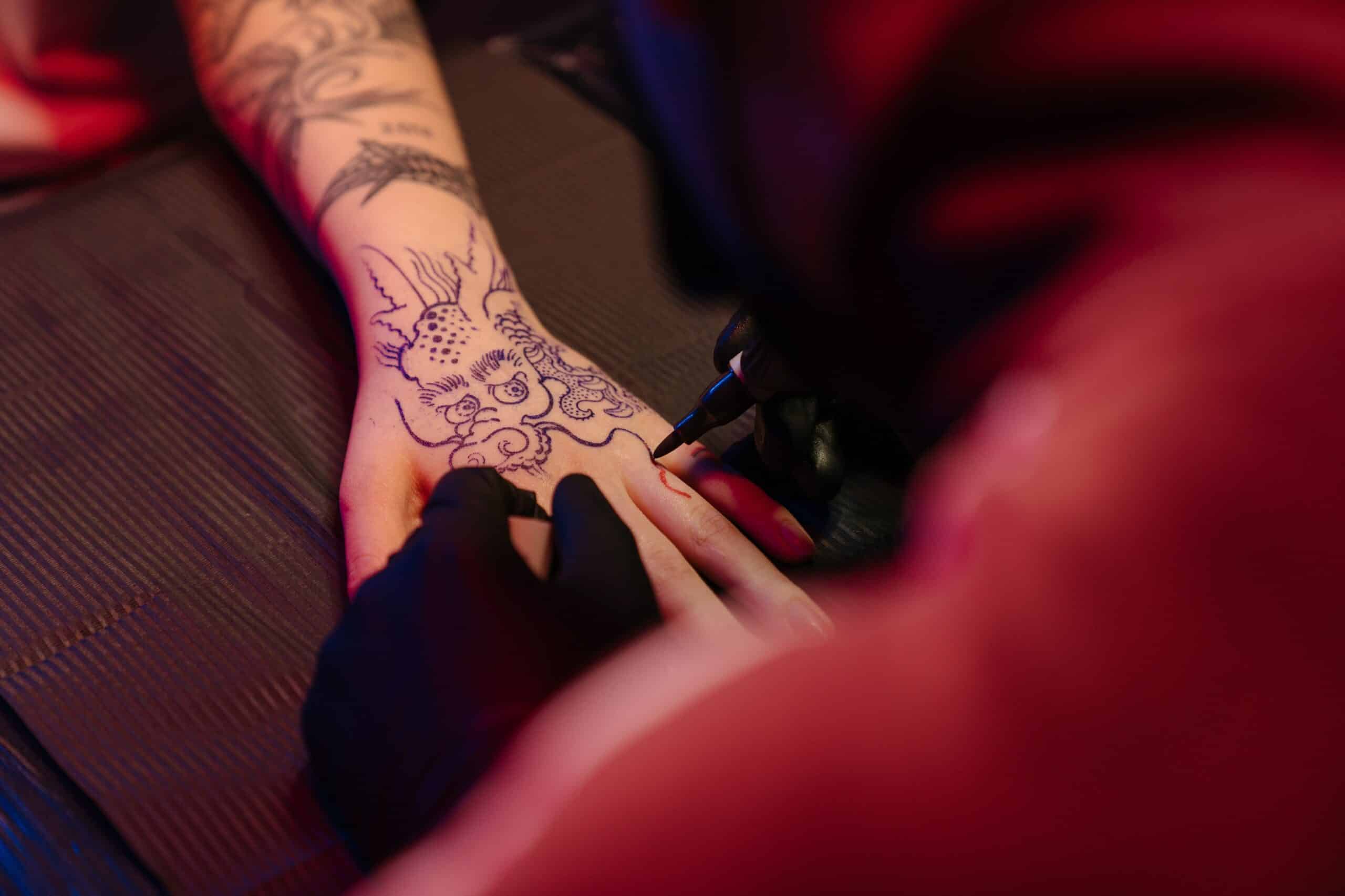 a woman getting a dragon tattoo on her hand