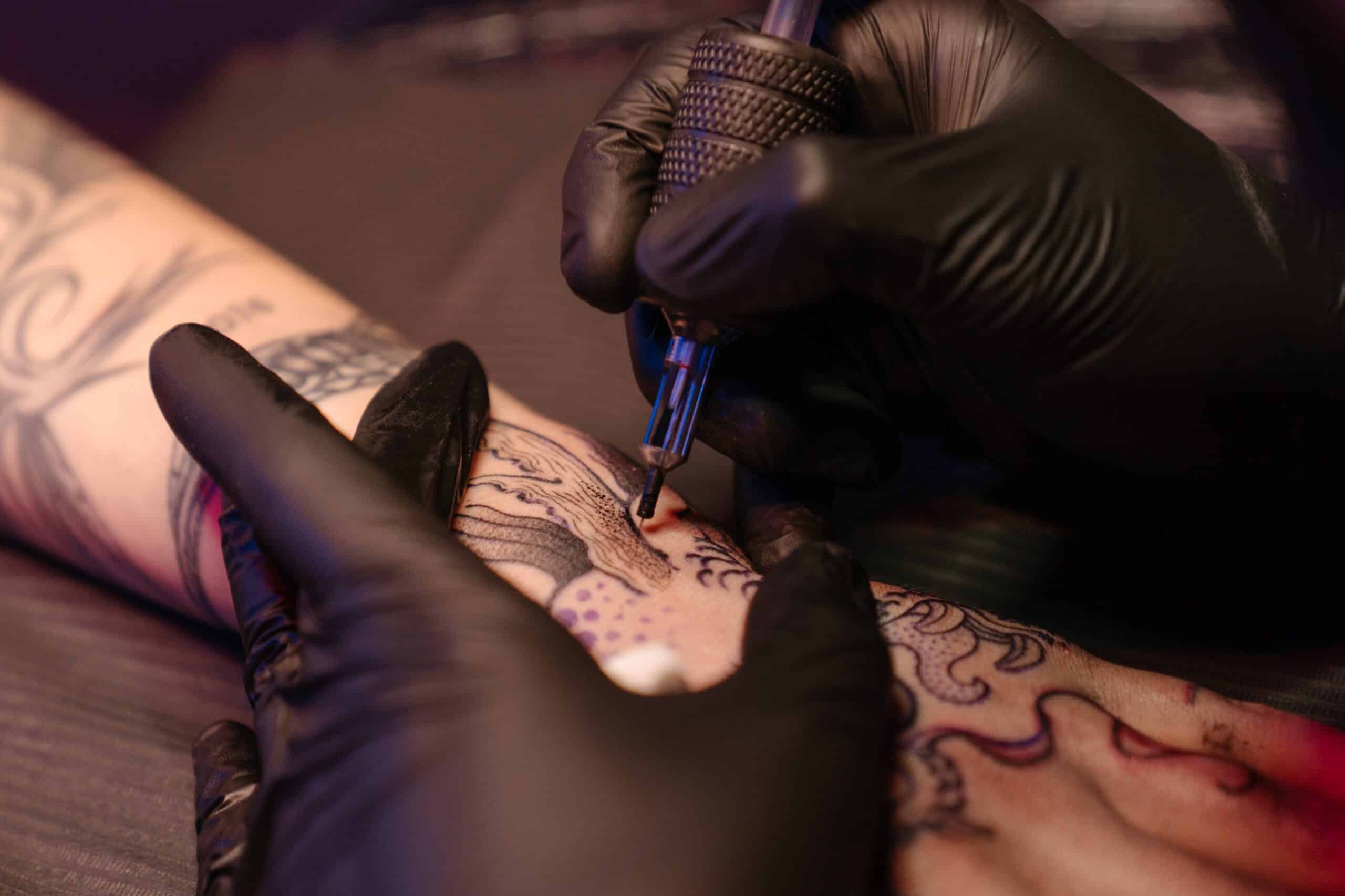 tattoo artist doing hand tattoo