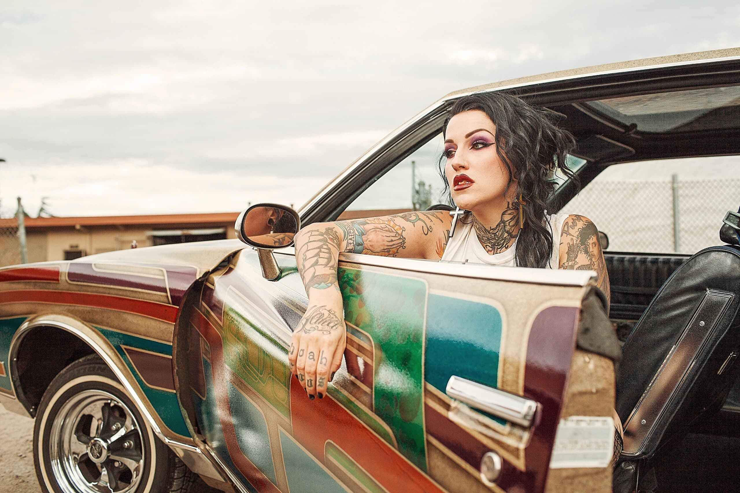 a tattooed woman in a classic car