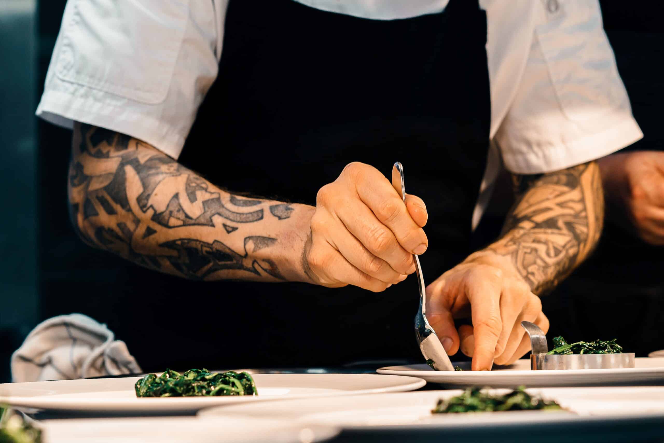 a chef plating with arm tattoos