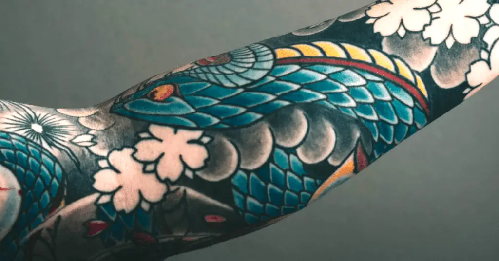 a man with colorful dragon tattoos on his arms
