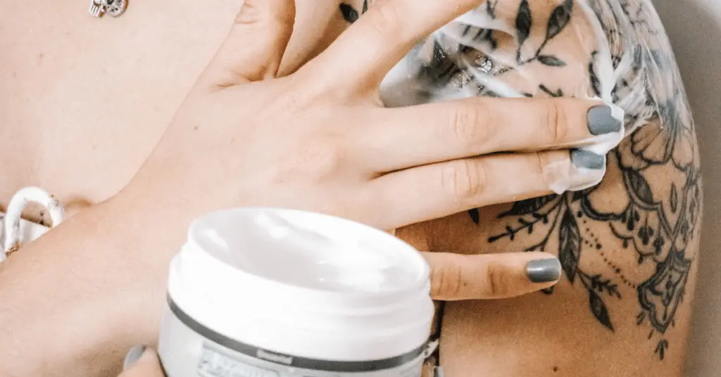 a woman applying moisturizer to her tattoo