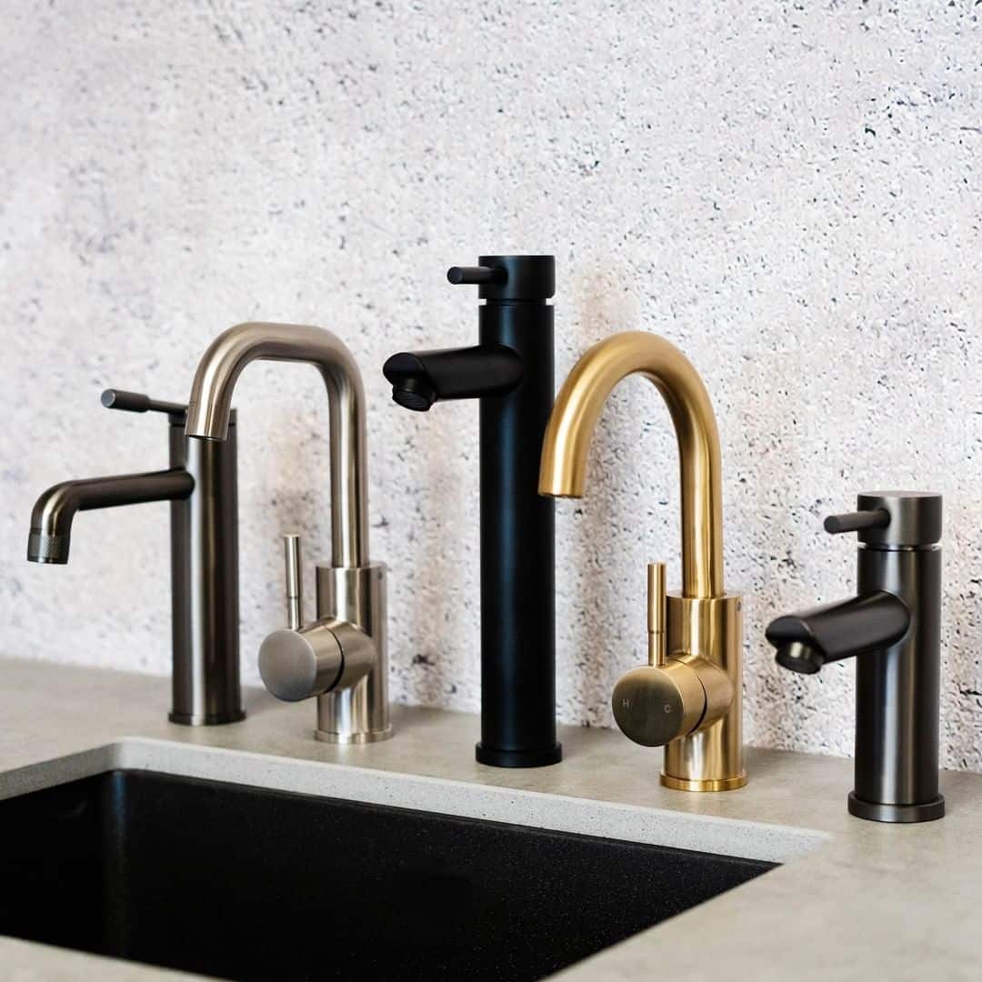 a series of elegant kitchen faucet on a rough concrete textured wall and light gray kitchen countertop