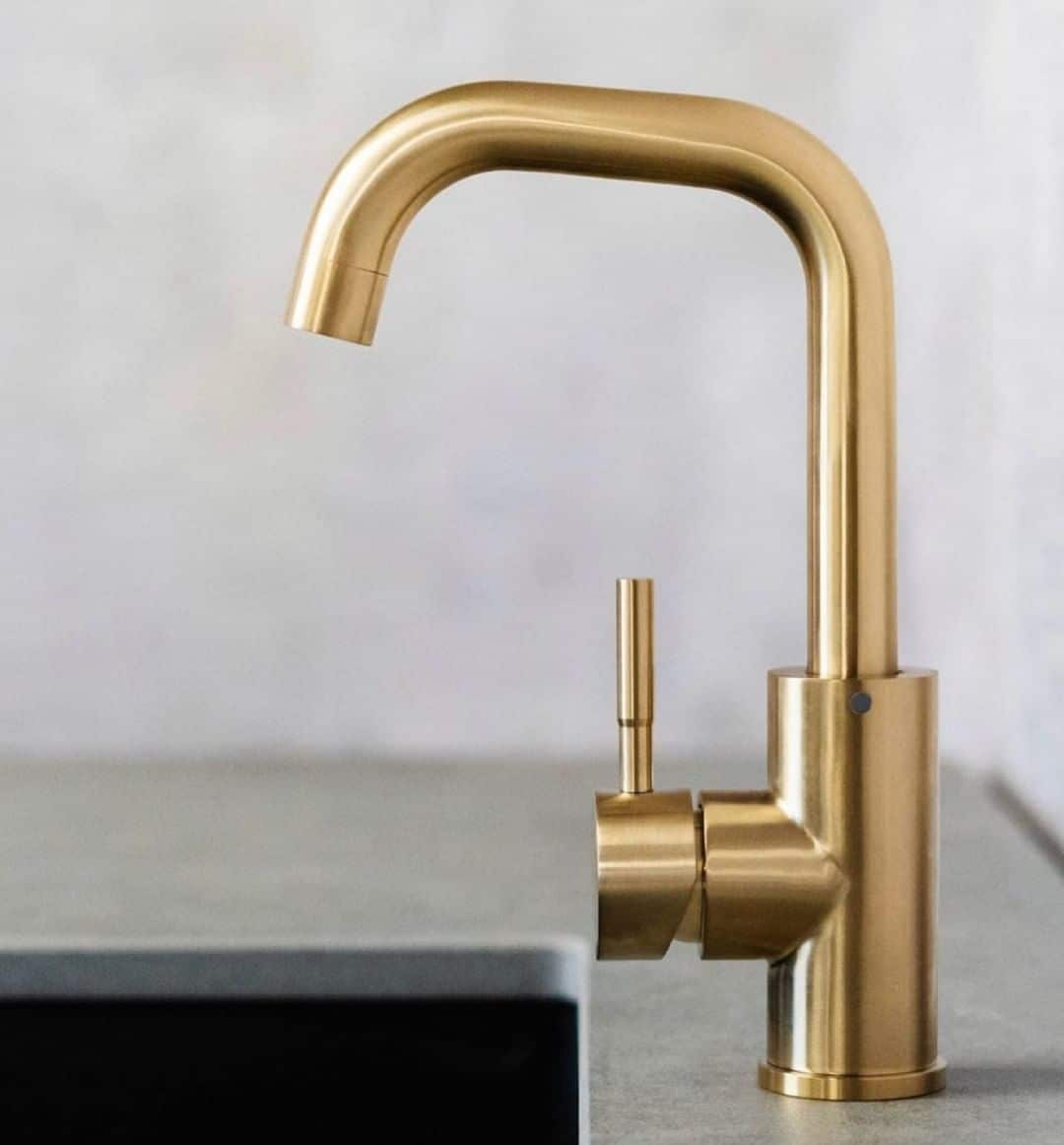 gold brass kitchen faucet on top of a light colored gray granite kitchen countertop