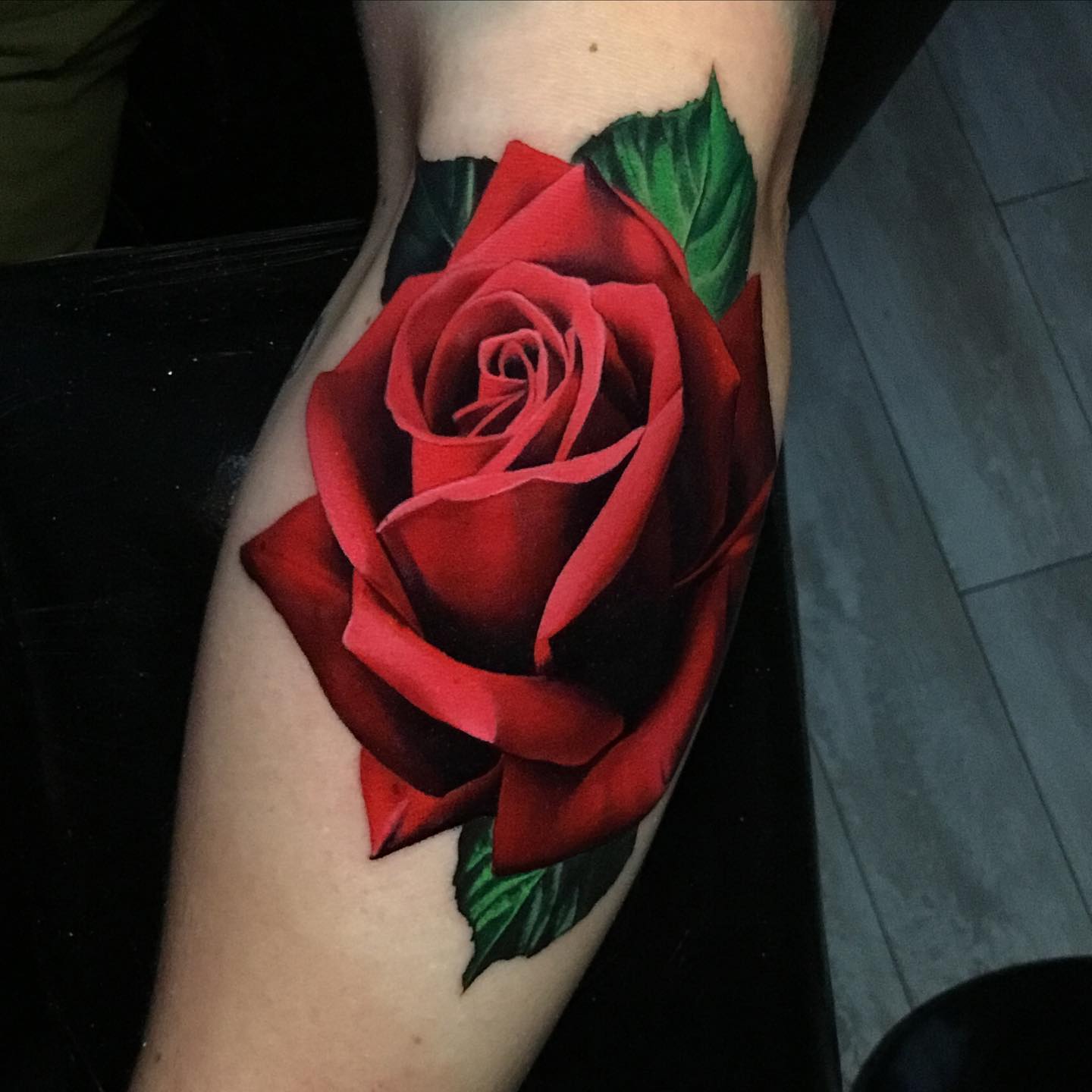a single red rose tattoo on a mans forearm