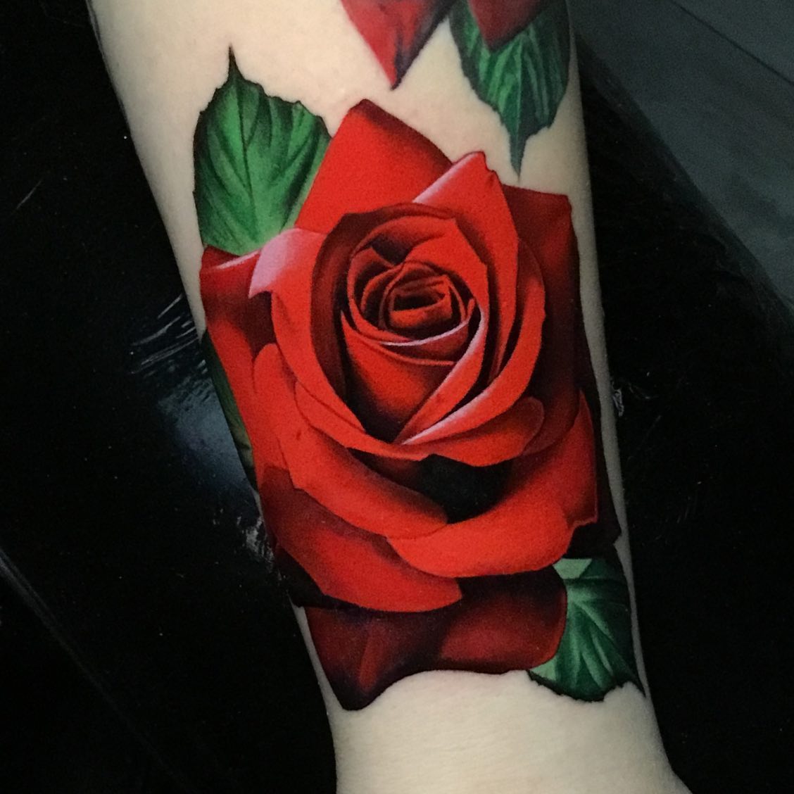single red rose tattoo on a womans forearms