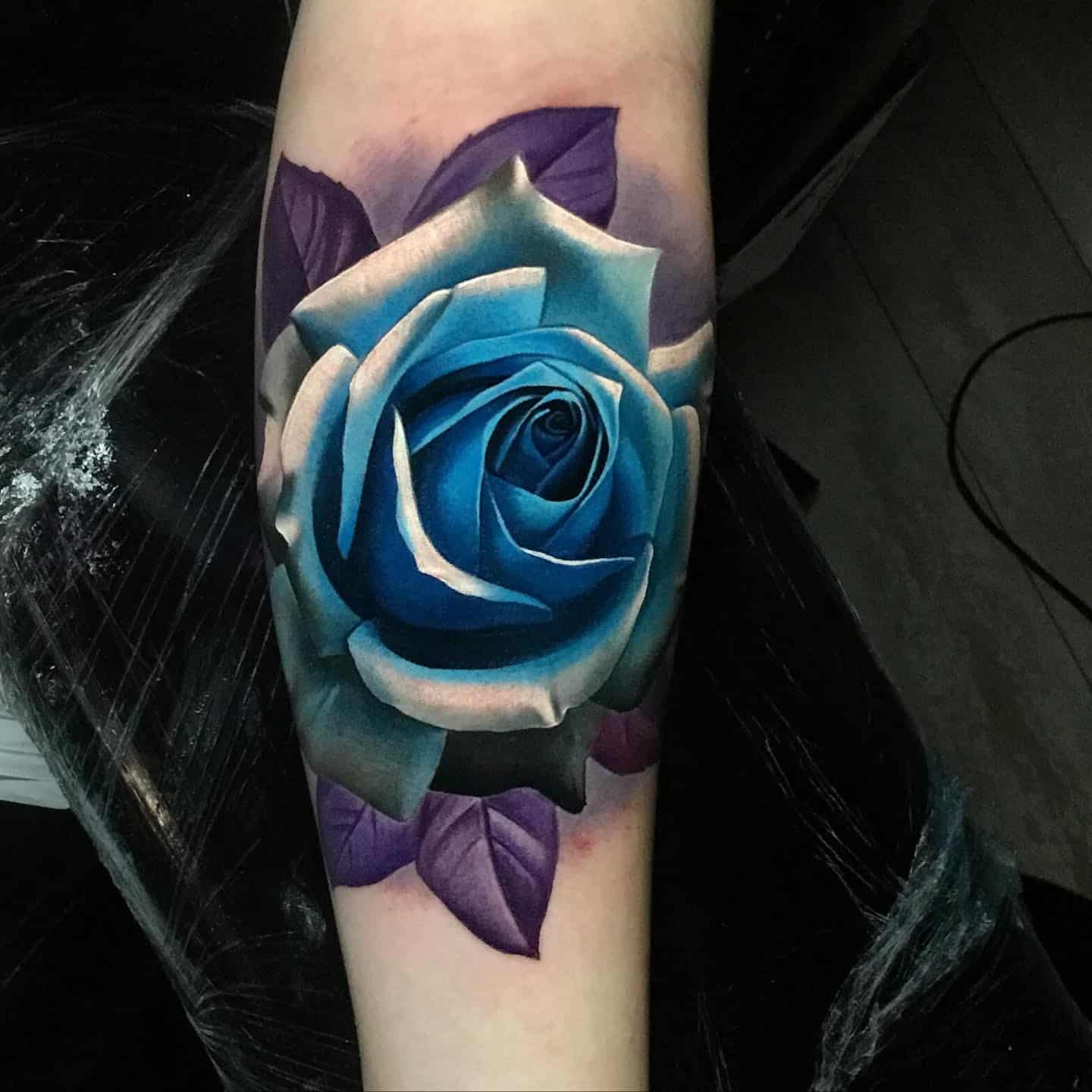 bright blue rose on a womans forearm