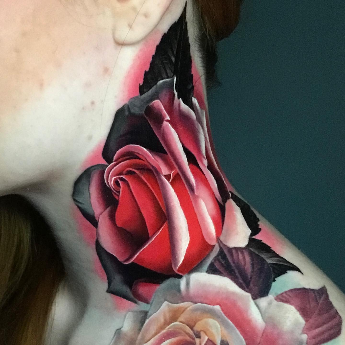 bright red rose tattoo on a womans neck
