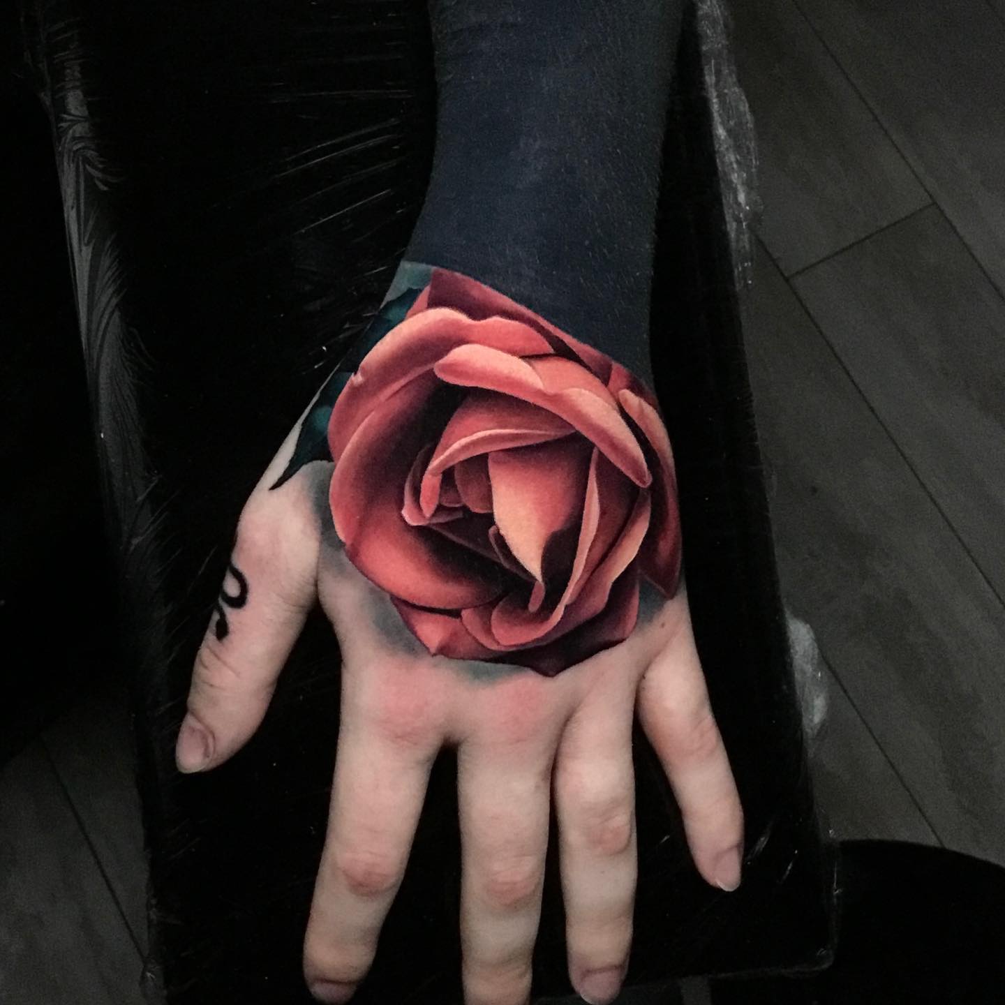detailed red rose tattoo on mans hands