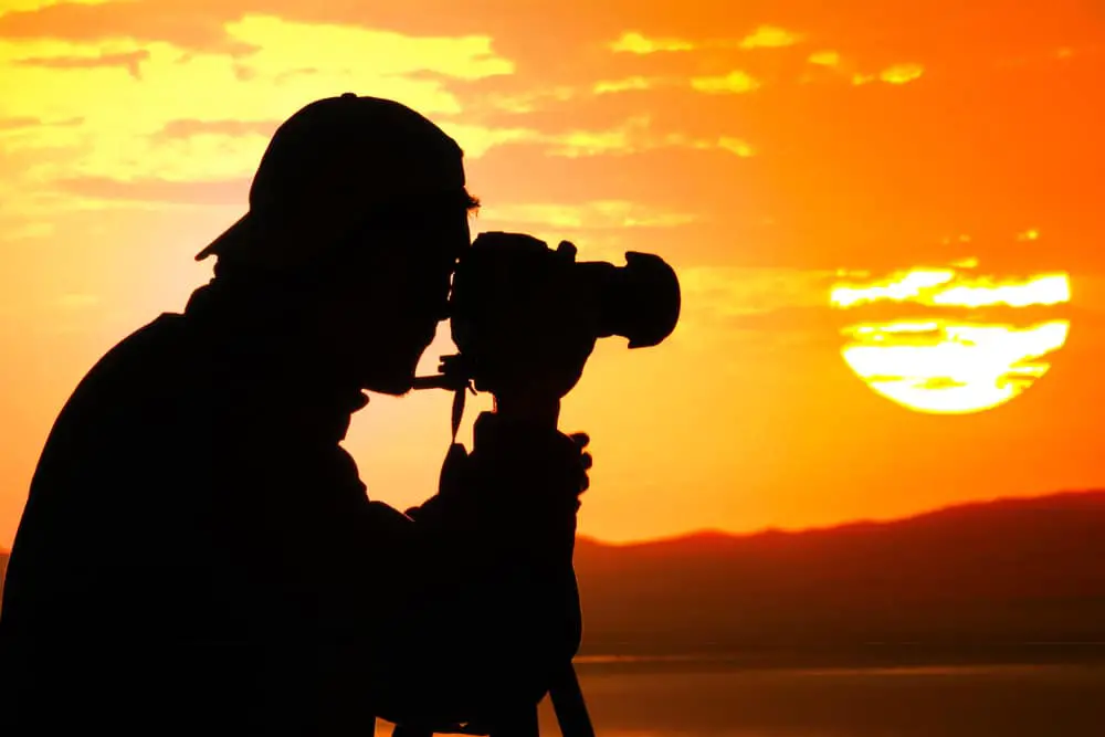man photographing a sunset